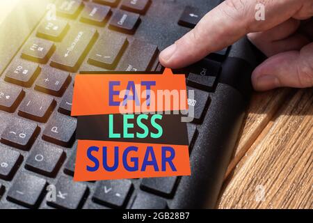 Didascalia di testo che presenta mangia meno zucchero. Concetto che significa ridurre l'assunzione di zucchero e mangiare una dieta sana cibi ricchi mani che puntano computer pressante Foto Stock