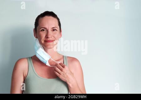 Una giovane donna toglie la sua maschera medica con un senso di gioia. Un posto per il copistace Foto Stock