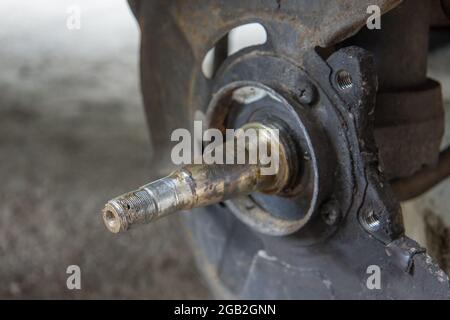 Assale anteriore esposto di un mozzo in una vettura. Assale anteriore sporco e usurato di un'autovettura, durante la sostituzione dei cuscinetti. Foto Stock