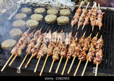 Hamburger al barbecue, cuori grigliati su spiedini e barbecue di fumo festa. Primo piano Foto Stock