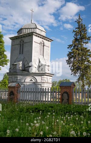 Vecchio campanile in legno vicino alla vecchia chiesa nella campagna della Lettonia Foto Stock