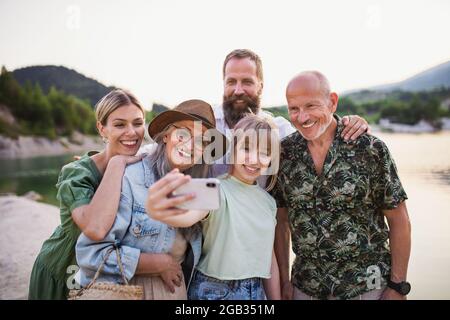 Felice multigeneration famiglia in viaggio escursionistico in vacanza estiva, prendendo selfie. Foto Stock