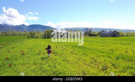 Felice ragazza di saltare sul campo di tulipani contro Sky Foto Stock