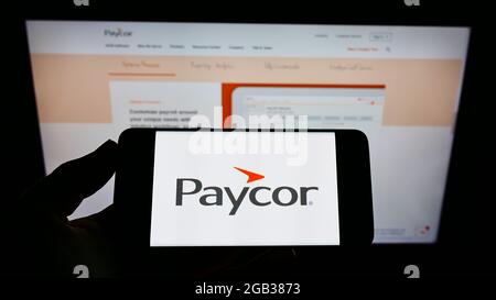 Persona che detiene il telefono cellulare con il logo della società americana di software HR Paycor HCM Inc. Sullo schermo davanti alla pagina web. Mettere a fuoco il display del telefono. Foto Stock