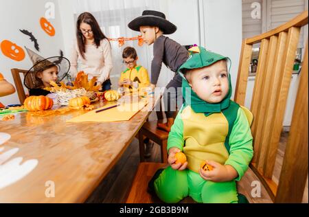 Bambino piccolo in costume fantasia verde seduto e piangendo Foto Stock