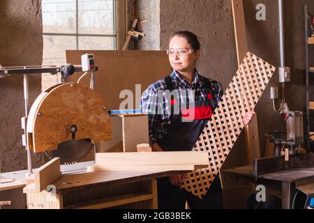 Falegname femminile con grata di legno vicino a sega circolare Foto Stock