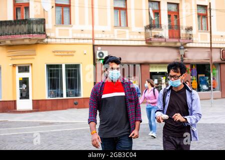 Due giovani amici multirazziali in maschere che chiacchierano all'aperto Foto Stock