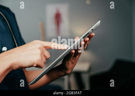 Donna caucasica che scrive su compressa digitale in clinica Foto Stock