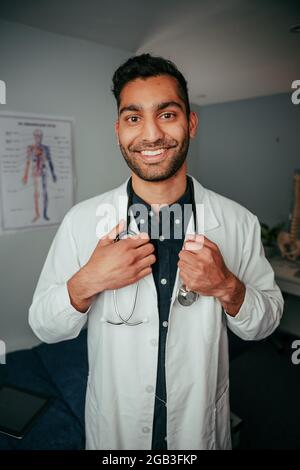 Razza mista sorridente medico maschile in piedi in clinica Foto Stock