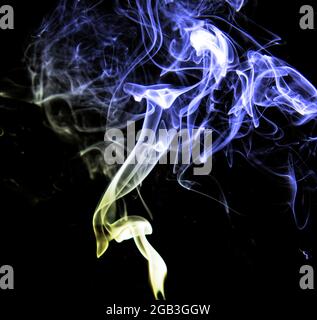 Vortice di fumo blu e giallo su sfondo nero che dà un effetto astratto Foto Stock