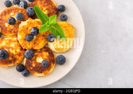 Torta al formaggio Cottage con mirtilli e menta in un piatto su sfondo grigio Foto Stock