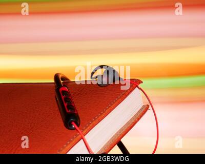 Cuffie musicali conservate su un libro di note con effetto luminoso sullo sfondo. Foto Stock