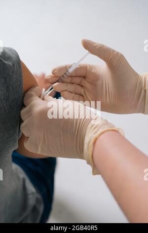 Dose di iniezione di vaccino cosod19 in spalla. Closeup mani di infermiere che vaccina il maschio. Foto Stock