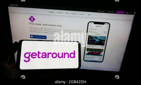 Persona in possesso di smartphone con logo della società di car sharing statunitense Getaround Inc. Sullo schermo davanti al sito Web. Mettere a fuoco il display del telefono.