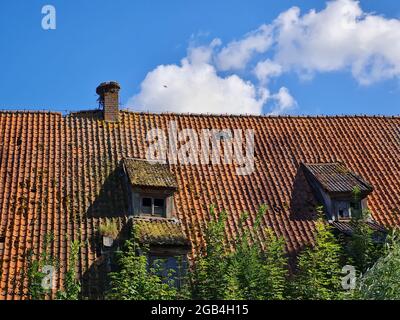 Vecchie finestre sul tetto della casa abbandonata e cielo blu con le nuvole Foto Stock