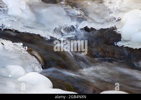 Acqua che scorre sotto ghiaccio fondente, concetto di riscaldamento globale Foto Stock