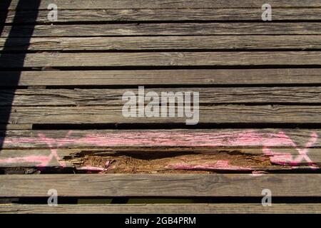 Tavole di legno danneggiate con segni rosa di vernice spray da contrassegnare come rinnovare Foto Stock