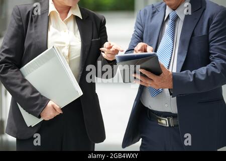 Immagine ritagliata dei partner aziendali di successo che puntano al tablet quando si discute dei dettagli del contratto Foto Stock