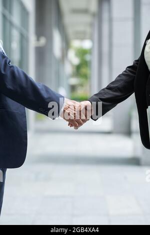 Immagine ravvicinata di imprenditori senior che scuotono le mani per confermare l'accordo dopo una riunione di successo Foto Stock