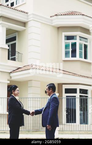 Cliente anziano scuotendo la mano del mediatore del bene immobile dopo l'acquisto della costruzione Foto Stock
