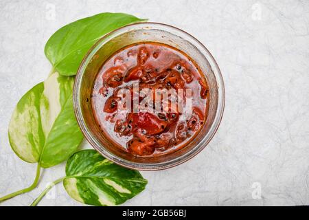 Indiano e pakistano Alubukhara o confettura di sottaceti di prugne Chutney dolce e piccante servito in ciotola quadrata bianca su sfondo bianco. Foto Stock