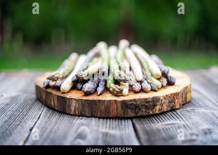 Germogli di asparagi verdi, viola e bianchi su tavola di legno. Vista dall'alto in piano. Fotografia alimentare Foto Stock