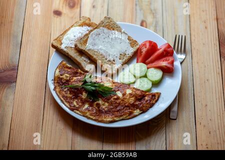 Frittata di formaggio con toast in cucina a casa su tavolo di legno. Fotografia alimentare Foto Stock