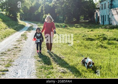 Donna anziana alla moda e la sua bambina godendo una passeggiata in campagna con il loro cane beagle - nonna e nipote felici insieme Foto Stock