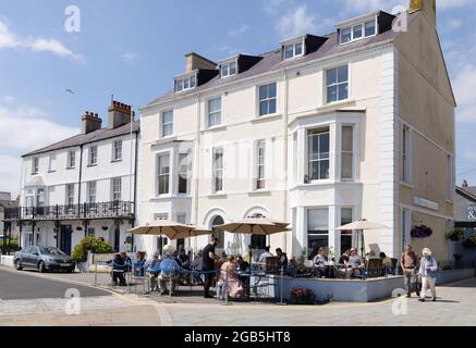 Wales cafe; persone che si siedono mangiare e bere all'aperto in un caffè sul lungomare in estate sole nel mese di luglio, Beaumaris, Anglesey, Galles Regno Unito Foto Stock