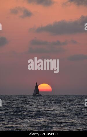 Barca a vela davanti al sole che tramonta sul Mar Mediterraneo Foto Stock