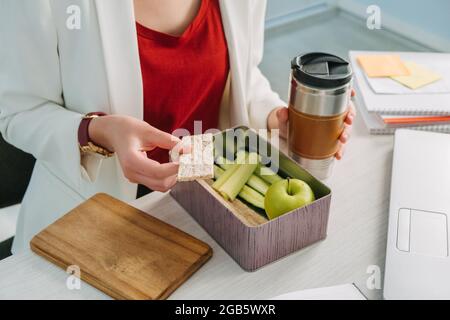 Mani femminili che tengono il pranzo zero rifiuti scatola, scatola di consegna di cibo con pasto sano perdita di peso dieta menu, cibo vegano sul posto di lavoro in ufficio. Ufficio Foto Stock