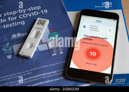 Un iPhone che mostra un messaggio di auto-isolamento durante la pandemia di Covid-19 nel 2021, con un test e un opuscolo Covid negativi. Foto Stock