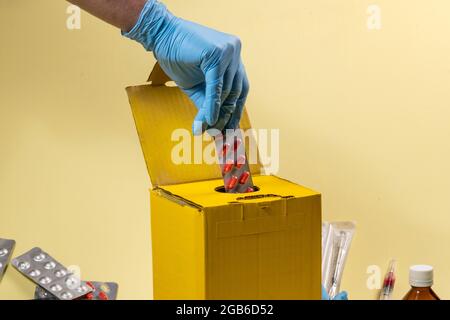 scatola gialla per lo smaltimento di prodotti contaminati o infettivi in ospedale o a domicilio. Blister di inserimento a mano Foto Stock