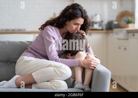 Il ragazzino riceve l'amore, la protezione e il sostegno della madre. Mamma coccolando figlio offeso bambino gridare sul divano Foto Stock