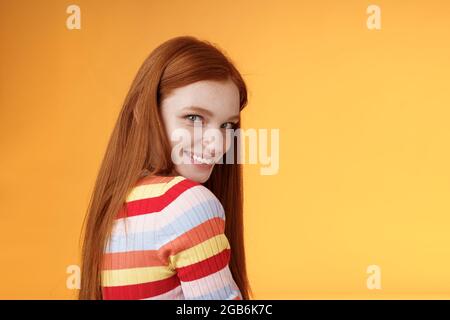 Tenerezza, romanticismo, concetto di seduzione. Attraente flirty giovane ragazza audace girata dietro guardare fotocamera a spalla sorridente coquetish sciocco Foto Stock