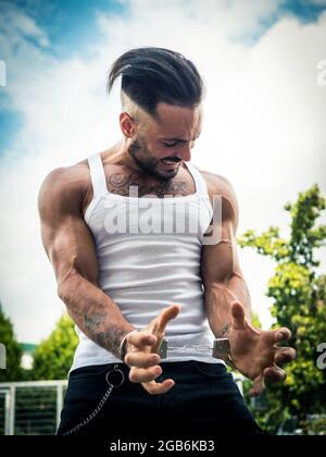 Giovane uomo forte che strezza manette nel parco Foto Stock