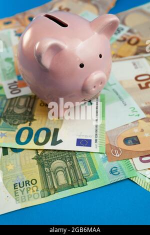banca di piggy sullo sfondo delle banconote in euro su sfondo blu Foto Stock