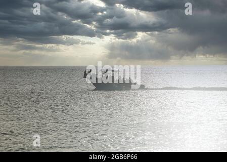 Silhouette di un motoscafo all'orizzonte contro il suggestivo cielo del tramonto, Cozumel Island, Messico Foto Stock