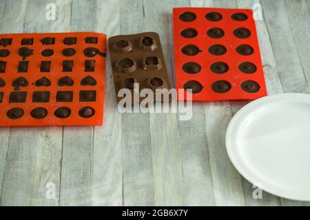 Processo graduale di produzione di cioccolatini al cioccolato fondente e ciliegie in cognac a casa. Le caramelle in stampi di silicone vengono preparate per il confezionamento. Cu Foto Stock