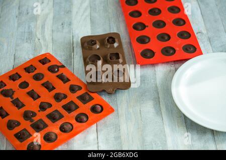 Processo graduale di produzione di cioccolatini al cioccolato fondente e ciliegie in cognac a casa. Le caramelle in stampi di silicone vengono preparate per il confezionamento. Cu Foto Stock