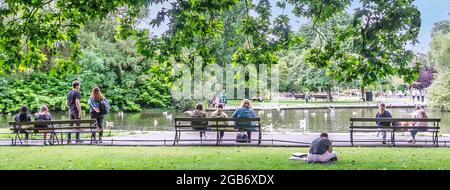 Le persone che si godono un pomeriggio di sole, presso il laghetto di anatre a St Stephens Green a Dublino, Irlanda. Foto Stock