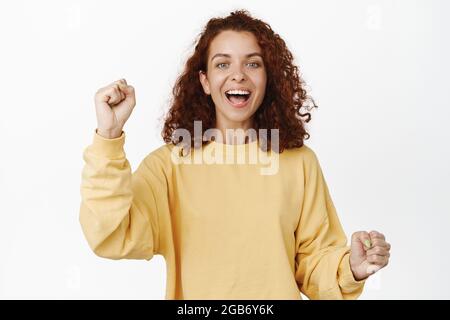 Immagine di una donna elettrizzata che canta, si fa motivare, ride e sorride, che canta per la squadra, festeggia, su sfondo bianco Foto Stock