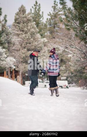 Una coppia amorevole cammina all'aperto tenendosi per mano durante il periodo invernale a Big Bear, CALIFORNIA. Foto Stock