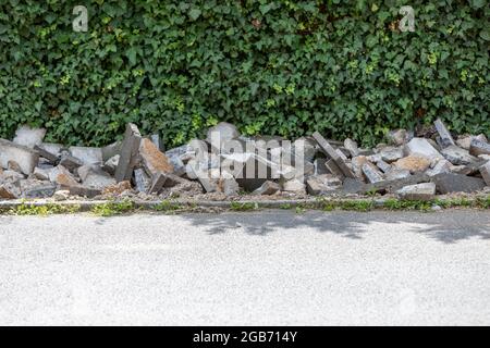 lavori di pavimentazione per rinnovare la passerella, distrutto vecchie pietre, siepe sullo sfondo Foto Stock