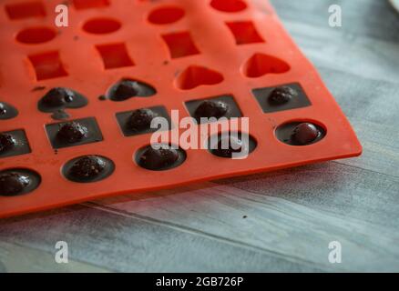 Processo graduale di produzione di cioccolatini al cioccolato fondente e ciliegie in cognac a casa. Le caramelle in stampi di silicone vengono preparate per il confezionamento. Cu Foto Stock