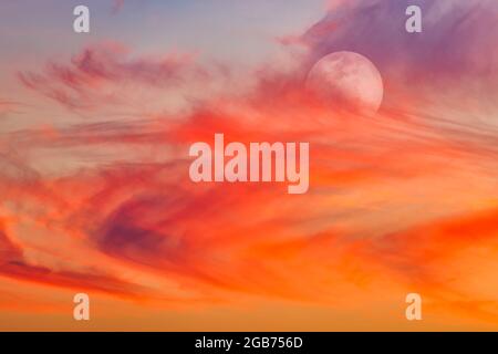 La Luna sta risplende nel cielo con le nuvole soffici contro UN cielo Sunset colorato Foto Stock
