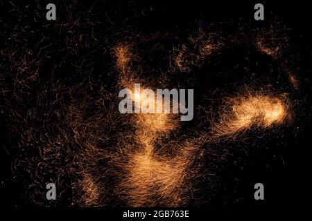 Bella sfondo astratto sul tema del fuoco, della luce e della vita. Braci brucianti che volano via particelle su sfondo nero. Foto Stock