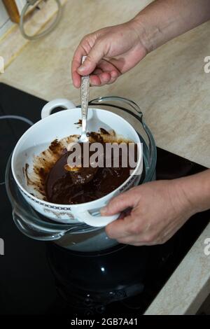 Processo graduale di produzione di cioccolatini al cioccolato fondente e ciliegie in cognac a casa. Il processo di fusione degli ingredienti per il cioccolato in Foto Stock