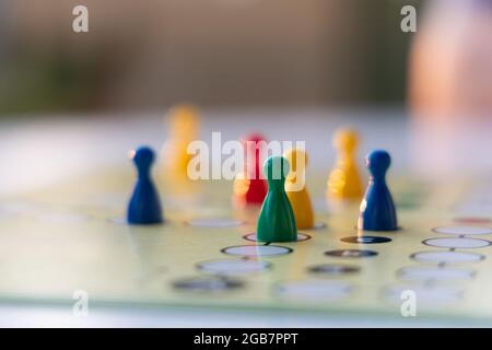primo piano di un gioco da tavolo con pezzi di gioco colorati - mettere a fuoco su un pezzo di gioco con campo di profondità ridotto. Primo piano sfocato e sfondo sfocato Foto Stock