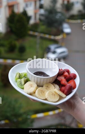 Idea di concetto di fonduta di cioccolato, donna che tiene frutta e piatto di cioccolato Foto Stock